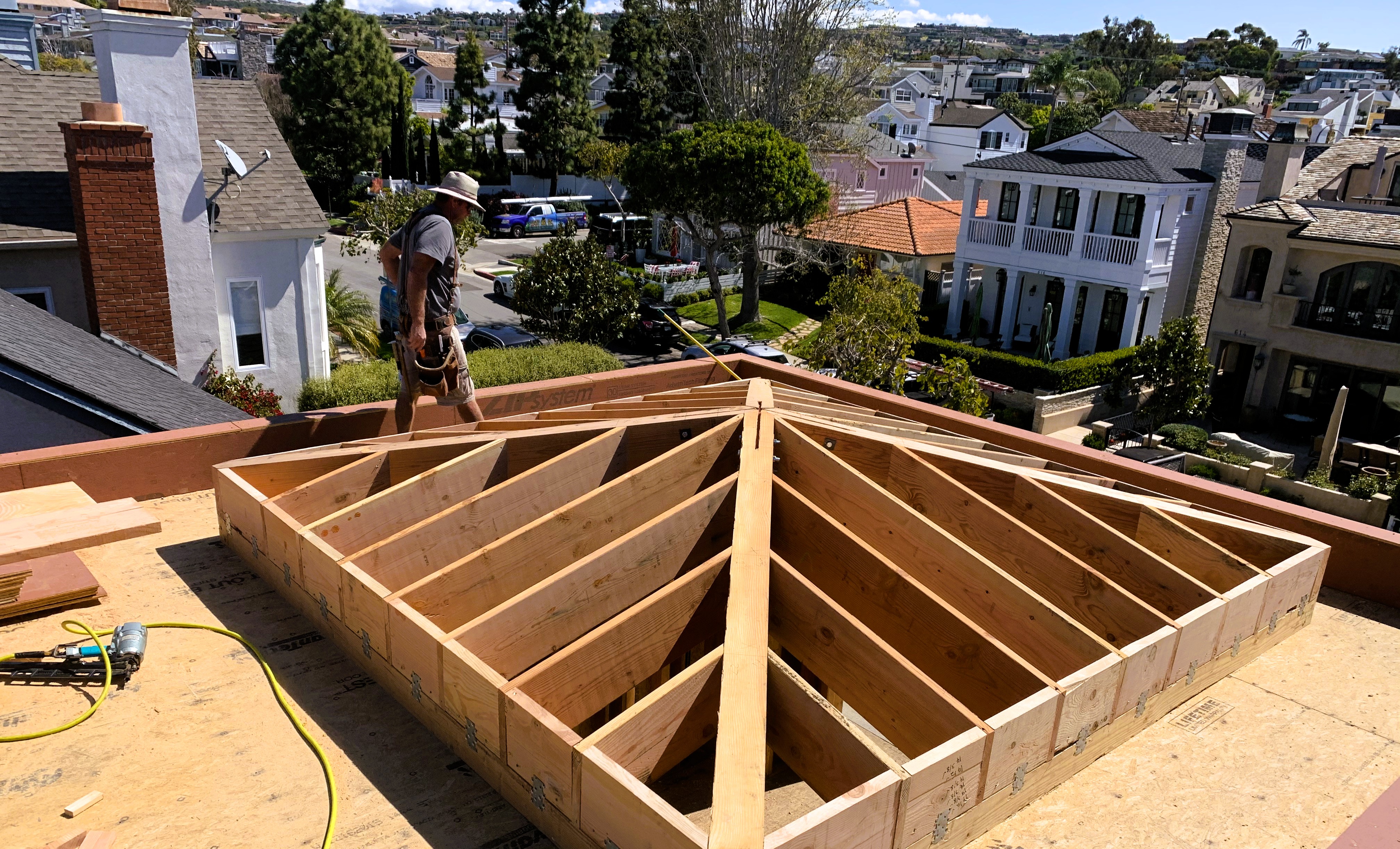 Skilled construction worker building precise wooden roof framing in upscale residential neighborhood
